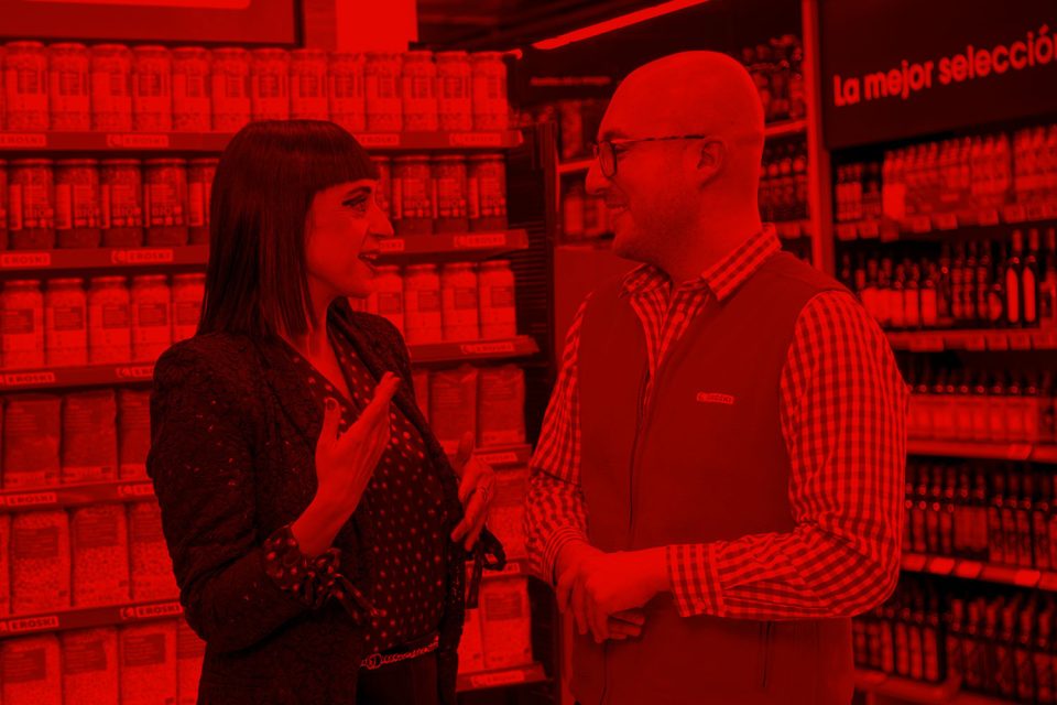 Clienta conversando con un trabajador de EROSKI en el pasillo de productos de alimentación del supermercado.