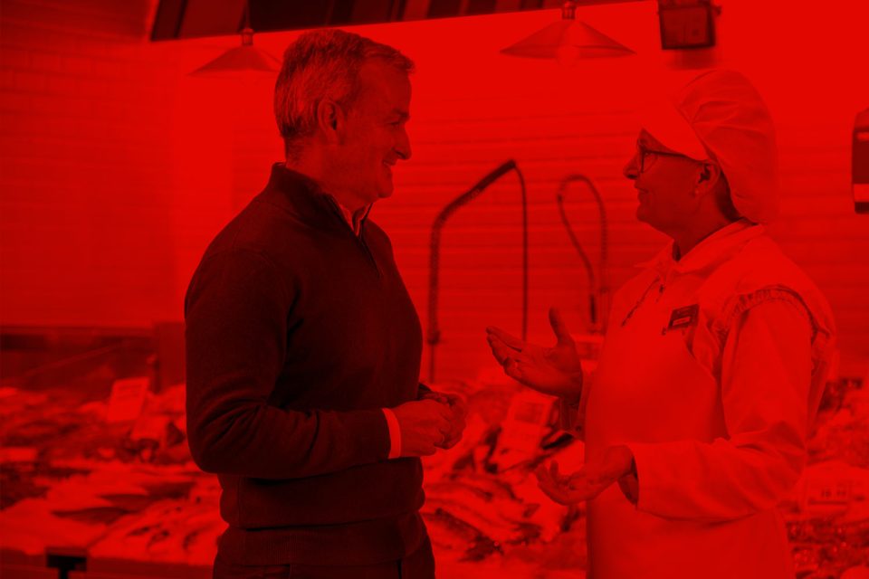 Cliente conversando con una trabajadora de EROSKI en la sección de pescadería del supermercado.