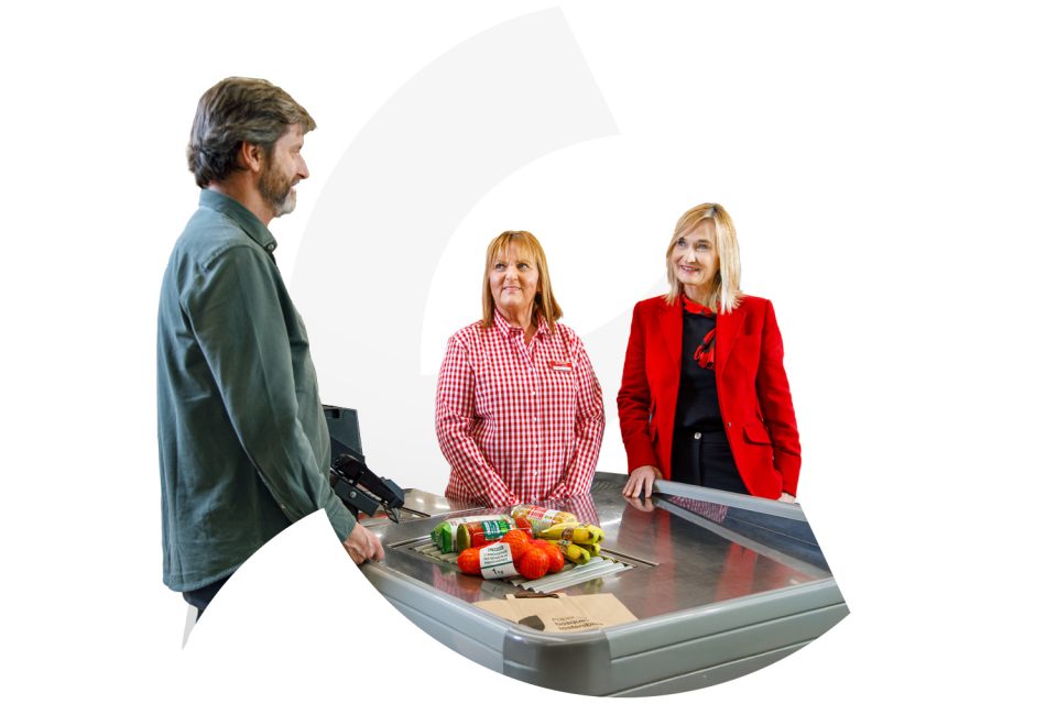 Professional de supermercat atesa una clienta en el taulell de xarcuteria i lliurant-li la seva compra.