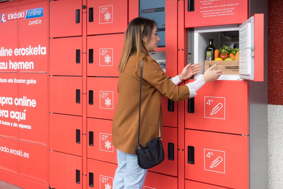Dona recull comanda en línia d'alimentació en taquilla refrigerada d'EROSKI.